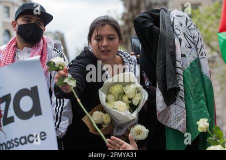 London, Großbritannien. Mai 2021. Eine Frau verteilt weiße Rosen, während Tausende von Menschen an einer Notkundgebung teilnehmen, die aus Solidarität mit dem palästinensischen Volk besteht, das vor der Downing Street von der palästinensischen Solidaritätskampagne, den Freunden von Al Aqsa, der Koalition „Stoppt den Krieg“ und dem palästinensischen Forum in Großbritannien organisiert wurde. Die Kundgebung fand aus Protest gegen israelische Luftangriffe auf Gaza, die Entsendung israelischer Truppen gegen Gläubige in der Al-Aqsa Moschee während des Ramadan und Versuche statt, palästinensische Familien aus dem Stadtteil Sheikh Jarrah in Ostjerusalem gewaltsam zu verdrängt. Kredit: Mark Kerrison/Alamy Live Nachrichten Stockfoto