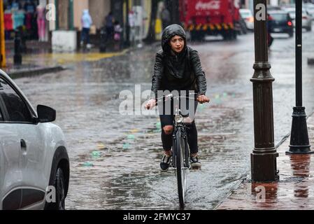 Non Exclusive: TOLUCA, MEXIKO - MAI 12: Eine Frau fährt auf einem Fahrrad mit Regenmantel bedeckt, da die Stadt mit starken Regenfällen dämmerte und mehr Regenfälle sind Stockfoto