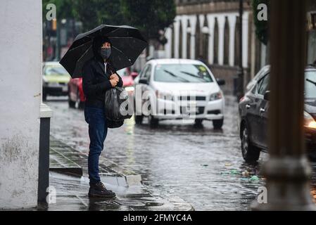 Non Exclusive: TOLUCA, MEXIKO - MAI 12: Eine Frau spaziert mit einem Regenschirm in die Innenstadt, um vor den Regenfällen geschützt zu werden, da die Stadt mit dem Regen aufgehört hat Stockfoto