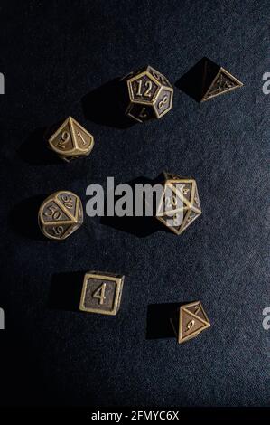 Vertikales Bild einer Reihe von Bronze-Metall-Rollenspiel Würfeln Sie auf einer schwarzen Oberfläche Stockfoto