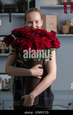 Mädchen hält einen riesigen Strauß roter Rosen in sich Hände Stockfoto