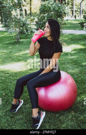 Junge fit gebräunte Frau Athlet trinkt Protein-Shake nach dem Training im Freien. Sporternährung. Weicher, selektiver Fokus. Stockfoto