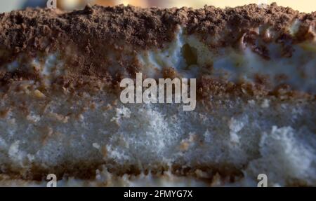 Extreme Nahaufnahme einer geschichteten Form, die einen süßen italienischen Dessertkuchen oder Gebäck namens Tiramisu mit Schokolade und Creme macht. Stockfoto