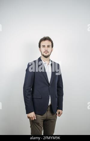 Junger, hübscher spanischer Geschäftsmann in einem schwarzen Anzug, auf dem er isoliert ist Ein weißer Hintergrund Stockfoto