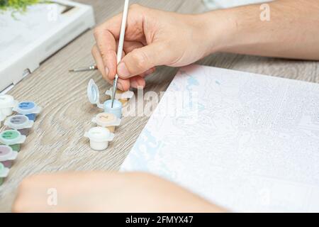 Eine mans Hand mit einem Pinsel zum Zeichnen von Nahaufnahme. Malen für Anfänger.Nahaufnahme, selektiver Fokus. Stockfoto