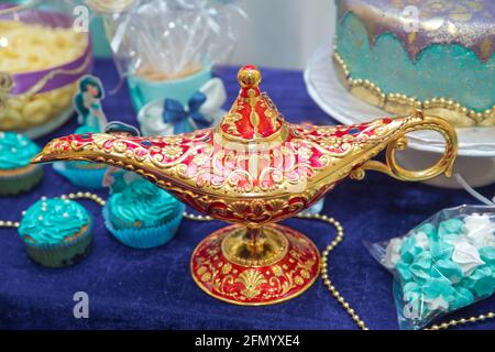 Eine magische Lampe über einem blauen Hintergrund. Aladdin Lampe der Wünsche auf dem Tisch. Aladdins magische Genie-Lampe in Rot und Gold auf blauem Hintergrund. Ein Stockfoto