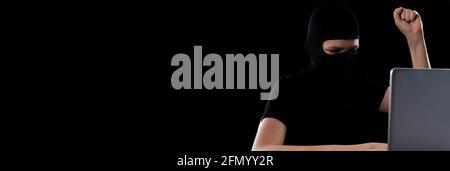 Ein Cyberkrimineller, der seine Programmiererfahrung nutzt, um in Unternehmens- und private Systeme einzudringen, um Daten zu stehlen. Cyberkriminelle hinter einem Laptop Stockfoto