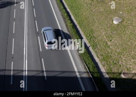 Schnelles, nicht erkennbares Auto fährt und bewegt sich auf der Straße, der Straße, der Autobahn und der Autobahn. Draufsicht, Bewegungsunschärfe und dunkle Schatten. Stockfoto
