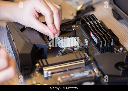 Anwendung von Thermopaste auf dem Prozessor-Chip für hochwertige Kühlung. Verteilen der Wärmeleitpaste mit einem speziellen Spatel Stockfoto