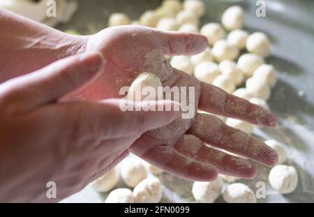 Der Prozess der Herstellung von hausgemachten Knödeln. Den Teig kneten. Frauenhände. Knödel, Pielmieni, Ravioli. Stockfoto