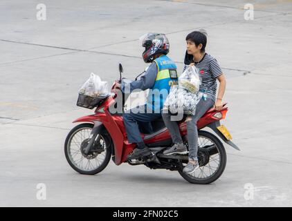 SAMUT PRAKAN, THAILAND, JULI 25 2020, EIN Taxifahrer auf einem Motorrad fährt mit einer Frau. Der mototaxi-Fahrer trägt einen Passagier. Stockfoto