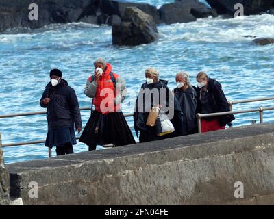 Penzance, Großbritannien. Mai 2021. Cornwall UK, St. Michaels Mount, House of Dragon. Viele der Darsteller ohne Gesichtsmasken. Die Schauspieler kehren von der Insel über eine halbe Meile offenes Meer zurück, eingewickelt in wasserfeste Umhänge, um die teuren Kostüme zu schützen. Eine raue Bootsfahrt von den Dreharbeiten auf der Insel St. Michaels Mount bis zur Hafenmauer von Marazion. April 2021. Kredit: Robert Taylor/Alamy Live Nachrichten Stockfoto