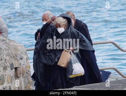 Penzance, Großbritannien. Mai 2021. Cornwall UK, St. Michaels Mount, House of Dragon. Viele der Darsteller ohne Gesichtsmasken. Die Schauspieler kehren von der Insel über eine halbe Meile offenes Meer zurück, eingewickelt in wasserfeste Umhänge, um die teuren Kostüme zu schützen. Eine raue Bootsfahrt von den Dreharbeiten auf der Insel St. Michaels Mount bis zur Hafenmauer von Marazion. April 2021. Kredit: Robert Taylor/Alamy Live Nachrichten Stockfoto