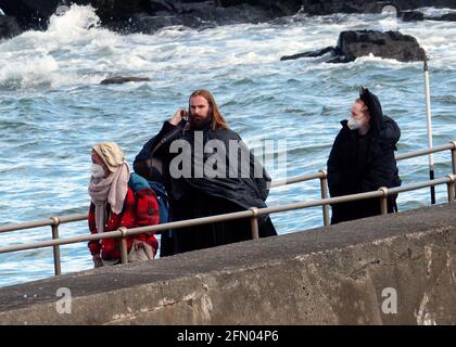 Penzance, Großbritannien. Mai 2021. Cornwall UK, St. Michaels Mount, House of Dragon. Viele der Darsteller ohne Gesichtsmasken. Die Schauspieler kehren von der Insel über eine halbe Meile offenes Meer zurück, eingewickelt in wasserfeste Umhänge, um die teuren Kostüme zu schützen. Eine raue Bootsfahrt von den Dreharbeiten auf der Insel St. Michaels Mount bis zur Hafenmauer von Marazion. April 2021. Kredit: Robert Taylor/Alamy Live Nachrichten Stockfoto