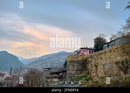 Bursa an bewölkten und regnerischen Tagen. Foto vom Bezirk tophane durch den ulu-Berg (uludag) im Hintergrund und mit pinkfarbenem Café-Restaurant Stockfoto