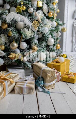 Weihnachtsgeschenk unter Weihnachtsbaum, eingewickelt mit Garn und Verpackung Papier mit Girlande-Lampen und Spielzeug dekoriert Stockfoto