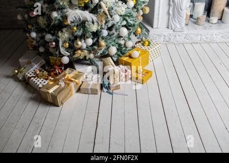 Weihnachtsgeschenk unter Weihnachtsbaum, eingewickelt mit Garn und Verpackung Papier mit Girlande-Lampen und Spielzeug dekoriert Stockfoto
