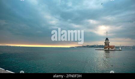 Der Maiden-Turm (kiz kulesi) istanbul, Türkei bei bewölktem Wetter und Sonnenuntergang über dem bosporus-Meer. Gruppen von Möwen, die auf dem Meer fliegen. Stockfoto