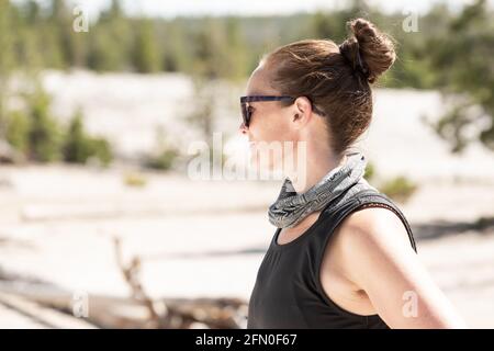 Frau mit Sonnenbrille blickt über das Yellowstone Geyser Basin Stockfoto