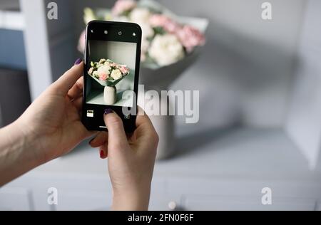 Blogger macht ein Foto von einem Blumenstrauß Stockfoto