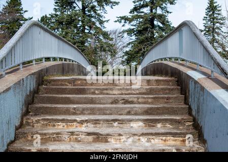 Die schmale Treppe zu einem alten Freischwinger-Steg. Die Zementbrücke ist abgenutzt und strukturiert. Stockfoto