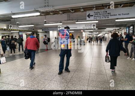 Straphangers erhalten den Impfstoff COVID-19 Janssen an der Pop-up-Impfstelle an der U-Bahnstation MTA 34th Street. Ein Arbeiter hält ein Plakat, um Menschen zu informieren, wo und wann sie Impfungen erhalten können. Jeder kann sich kostenlos impfen lassen, auch Besucher aus anderen Teilen des Landes oder aus anderen Ländern nach New York. Jeder, der eine Impfung erhält, erhält eine unbegrenzte 7-Tage-Metrokarte für Busse und U-Bahnen. Pop-up-Seiten sind auf Befehl von Gouverneur Andrew Cuomo geöffnet. (Foto von Lev Radin/Pacific Press) Stockfoto