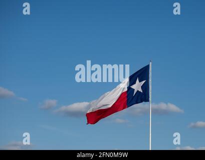 Texas Lone Star State Flagge mit weißem Stern auf blauem Hintergrund entfaltet an einem windigen Tag. Blauer Himmel mit Wolken im Hintergrund. Das Bild verfügt über Kopierspeicher. Stockfoto