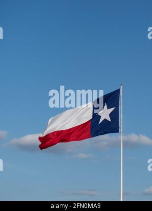 Texas Lone Star State Flagge mit weißem Stern auf blauem Hintergrund entfaltet an einem windigen Tag. Blauer Himmel mit Wolken im Hintergrund. Das Bild verfügt über Kopierspeicher. Stockfoto