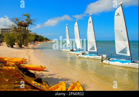 Vier kleine Segelboote am Ufer eines tropischen jamaikanischen Strandes, bei sonnigem Wetter. Stockfoto