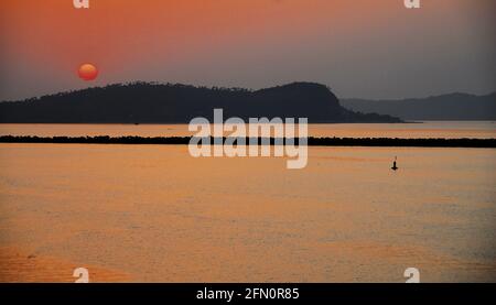 Eine rote Sonne bei Sonnenuntergang am Atlantischen Ozean, Foto aufgenommen in Guinea, Westafrika. Stockfoto