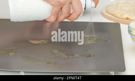 Frau mit Olivenöl Spray auf der Backform. PizzaSchritt für Schritt Backprozess, Rezept Stockfoto