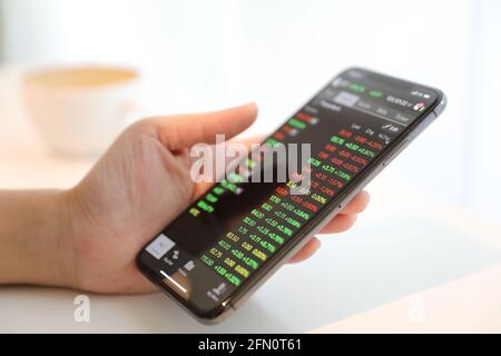 Weibliche hand mit Smartphone Handel Börse online im Coffee Shop, Business Konzept Stockfoto