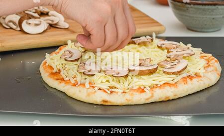 Mozzarella-Pilz Pizza Schritt für Schritt Rezept. Pizzateig mit Pilzscheiben belegen Stockfoto