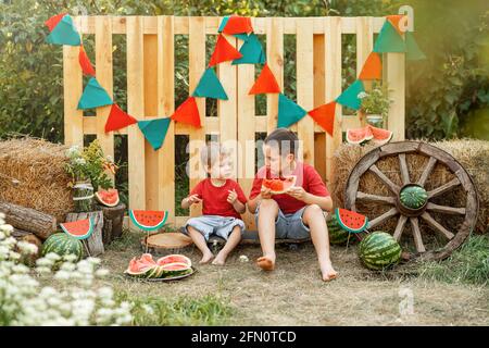 Lustige Kinder essen Wassermelone im Freien im Garten. Sommerzeit. Stockfoto