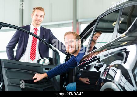 Verkäufer oder Autoverkäufer und Klienten oder Kunden im Autohaus präsentiert die Innenausstattung von Neu- und Gebrauchtwagen im Autohaus Stockfoto