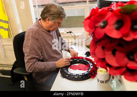 William Sellick macht einen Mohnkranz in der Mohn-Fabrik der Royal British Legion, 20 Petersham Road, Richmond, London, Großbritannien. Die Poppy Factory beschäftigt Ex-Service-Mitarbeiter, die Mohnblumen, Erinnerungskreuze, Sprays und Kränze für den jährlichen Appell- und Gedenktag der Royal British Legion anstellen. Die Poppy Factory ist auch für die Anpflanzung und Ausrichtung des „Field of Remembrance“ in der Westminster Abbey verantwortlich. The Royal British Legion's Poppy Factory, 20 Petersham Road, London, Großbritannien. 16 Okt 2013 Stockfoto