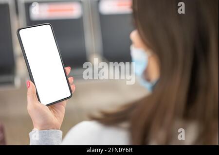 Übergibt Reisende per Smartphone in der Flughafenlounge. Frau hält Handy in der Flughafenlounge in der Hand. Aus Der Perspektive Einer Frau, Die Mobil Nutzt Stockfoto
