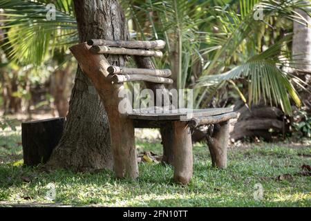 Handgemachte Holzbank unter dem Baum, der perfekte Ort zum Sitzen und Entspannen. Stockfoto