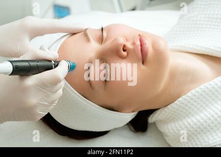 Eine Frau erhält Laserbehandlung des Gesichts in einer Kosmetikklinik wird ein Konzept der Hautverjüngung entwickelt. Laserpeeling Stockfoto