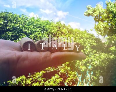 Text 'Italien' auf Weinkorken mit der italienischen Landschaft als Hintergrund geschrieben. Konzept der Reise nach Italien. Stockfoto