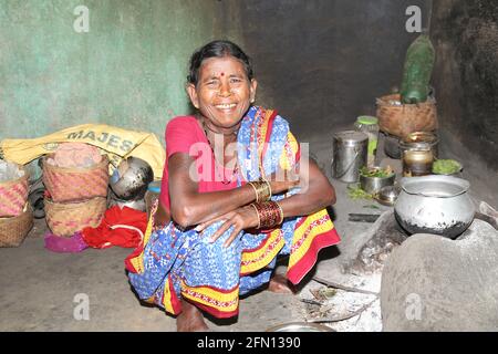 Die alte Baiga-Stammesfrau sitzt in der Nähe eines Lehmherdes und lächelt. BAIGA-STAMM, Chiyapadar Baiga Dorf von Odisha, Indien Stockfoto