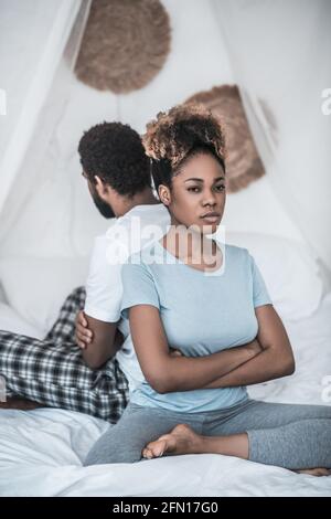 Verärgerte Frau, die mit dem Rücken zu ihrem Mann sitzt Stockfoto