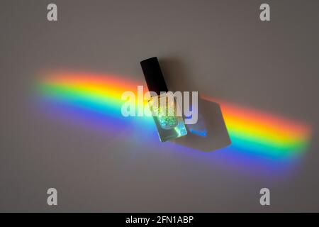 Holographische Nagellack in einer Prismenregenbogenlinie auf einem Grau Papier Stockfoto