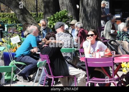 Stockholm, Schweden - 12. Mai 2021: Menschen, die das sonnige, warme Wetter im Café im Kungstradgarden Park genießen. Stockfoto