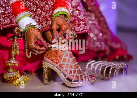 Atemberaubende indische Braut trägt Sandalen auf ihrer Hochzeit. Stockfoto