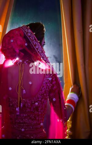 Atemberaubende indische Braut in hindurot gekleidet traditionelle Hochzeitskleidung mit Make-up und Schmuck. Stockfoto