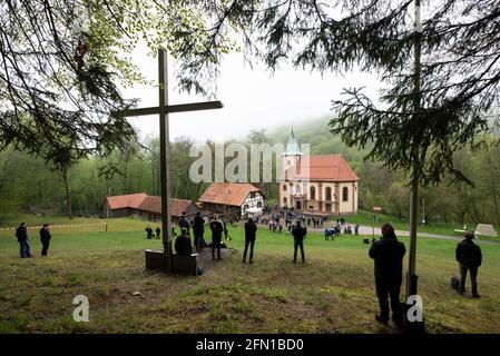 Wachstedt, Deutschland. Mai 2021. Gläubige stehen bei der alternativen Männerwallfahrt unter dem Motto 'Komm Herr, segne uns' vor der Wallfahrtskirche Klüschen Hagis hinter einem Holzkreuz. Himmelfahrt ist der Tag der Männerwallfahrt nach Klüschen Hagis in der Diözese Erfurt. Wie im vergangenen Jahr wurde die traditionelle Wallfahrt wegen Corona abgesagt. Quelle: Swen Pförtner/dpa/Alamy Live News Stockfoto