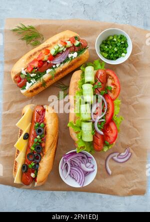 Köstliche frisch gekochte Hotdogs mit Würstchen, Gemüse, Käse und Sauce auf einem Stockfoto