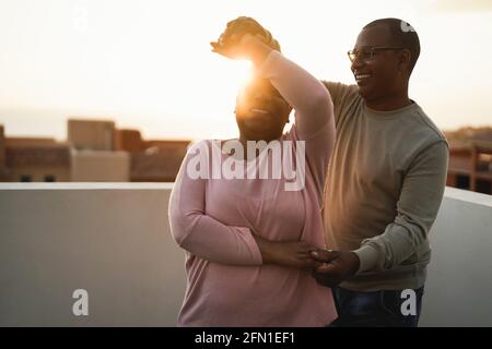 Afrikanisches Paar tanzt im Freien bei Sonnenuntergang im Sommer - Fokus auf Männergesicht Stockfoto