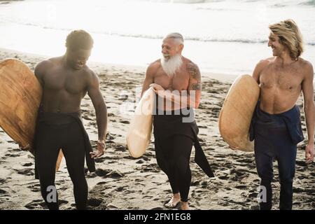 Multi-Generationen-Surfer-Männer mit Spaß am Strand - Hauptfokus auf Senior Face Stockfoto